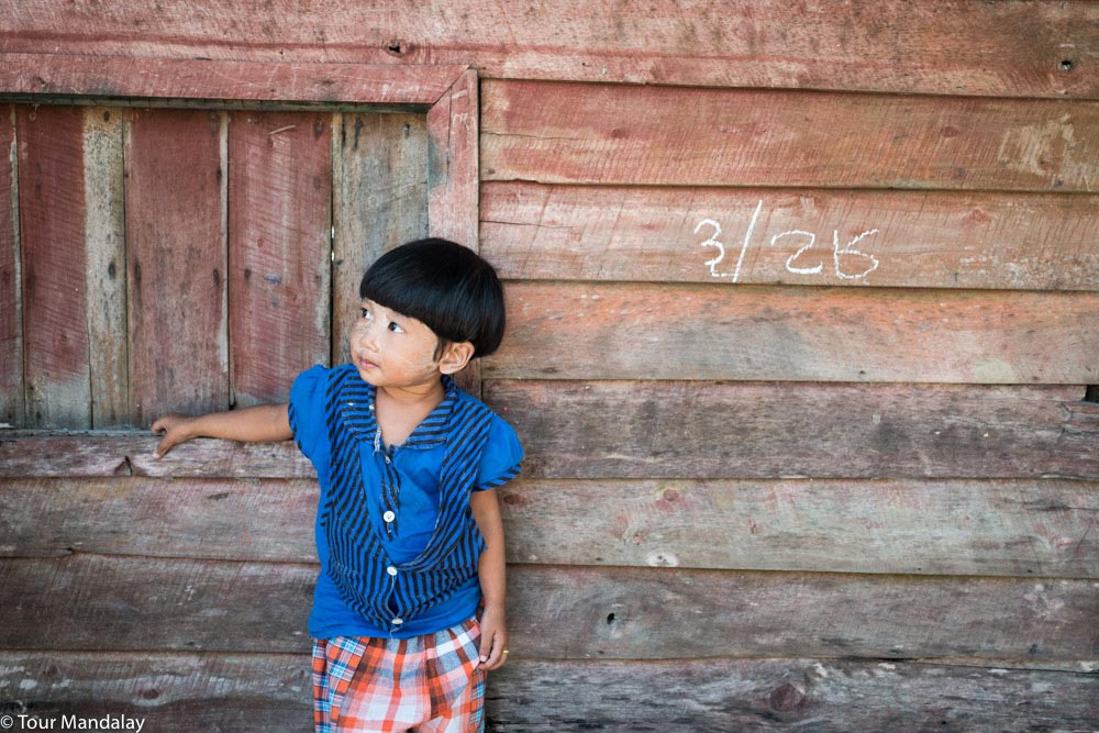 A Moken child poses in front of a wooden shack